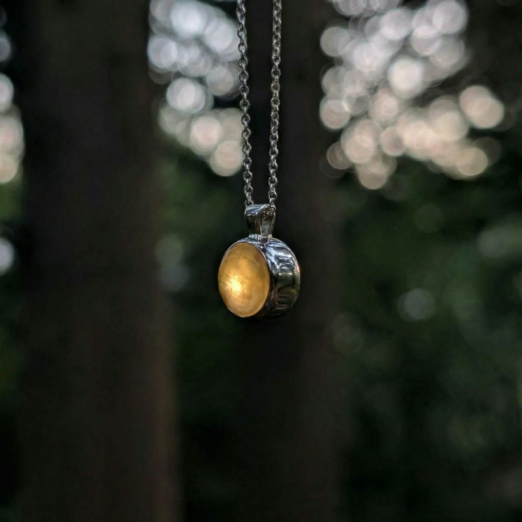 Louis Jacques pendant glowing softly against woodland bokeh